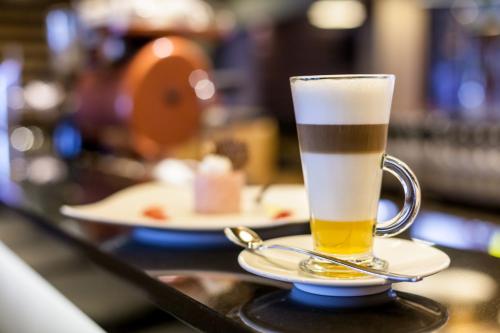 a glass of beer sitting on a bar with a plate of food at Aquaticum Debrecen Termal & Wellness Hotel in Debrecen