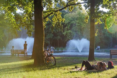 two people laying on the grass in a park with a fountain at Aquaticum Debrecen Termal & Wellness Hotel in Debrecen