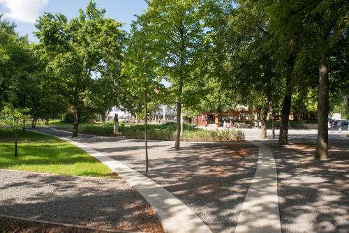 a walkway in a park with trees and grass at Aquaticum Debrecen Termal & Wellness Hotel in Debrecen