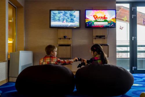 two children playing a video game in a room at Aquaticum Debrecen Termal & Wellness Hotel in Debrecen