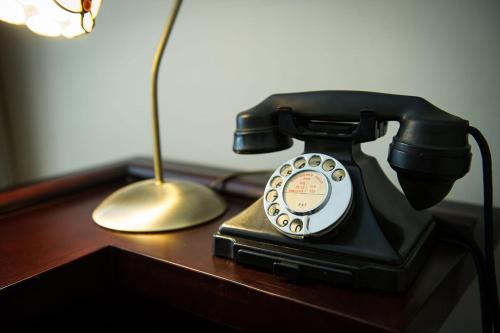 a black phone sitting on a desk next to a lamp at Claverton Hotel in Battle