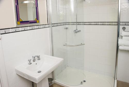 a white bathroom with a sink and a shower at Claverton Hotel in Battle