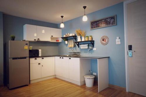 une cuisine avec des armoires blanches et un mur bleu dans l'établissement My Resort Hua Hin A502, à Hua Hin