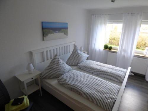 ein Schlafzimmer mit einem Bett mit zwei Kissen und einem Fenster in der Unterkunft An der Flut 193 in Wilhelmshaven
