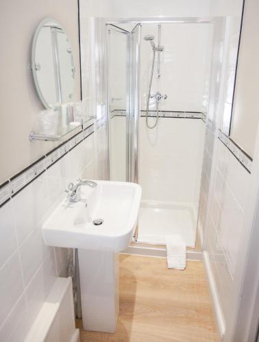 a white bathroom with a sink and a shower at Claverton Hotel in Battle