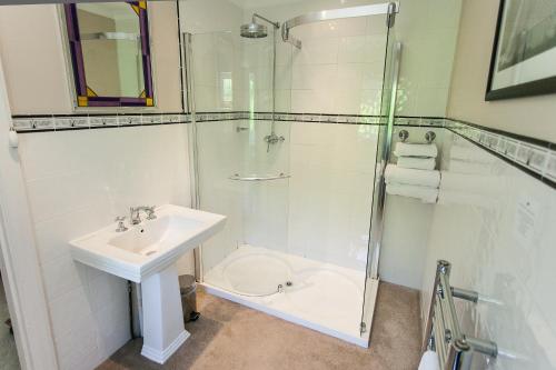 a white bathroom with a sink and a shower at Claverton Hotel in Battle