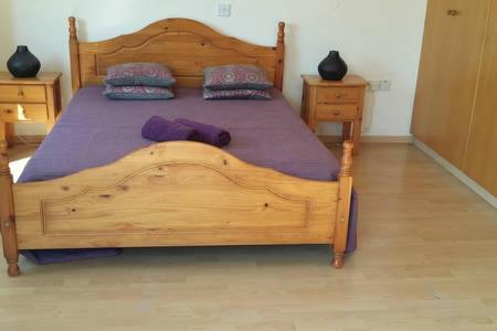 a bedroom with a wooden bed with purple sheets and pillows at Larnaka Beach House 3 in Larnaka