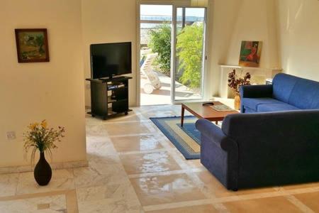 a living room with a blue couch and a tv at Larnaka Beach House 3 in Larnaka