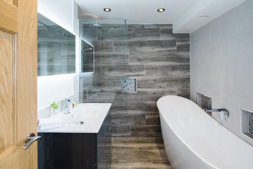 a bathroom with a bath tub and a sink at 1863 Restaurant with Rooms in Pooley Bridge