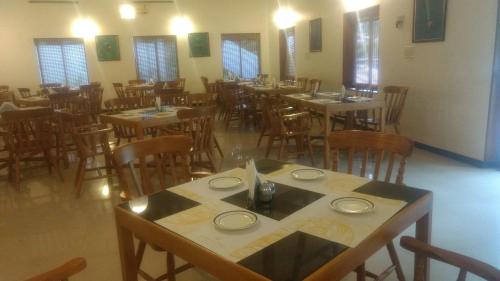 a dining room with tables and chairs and windows at Abad Harmonia Ayurvedic Beach Resort in Kovalam