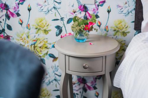 a small table with a vase of flowers on it at 1863 Restaurant with Rooms in Pooley Bridge