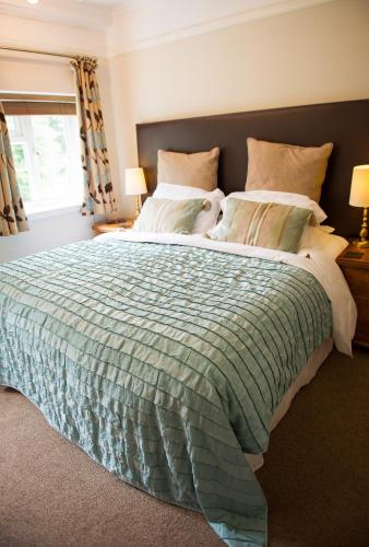 a bedroom with a large bed with a green comforter at Claverton Hotel in Battle