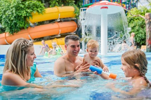 a man and woman and a child in a swimming pool at Aquaticum Debrecen Termal & Wellness Hotel in Debrecen