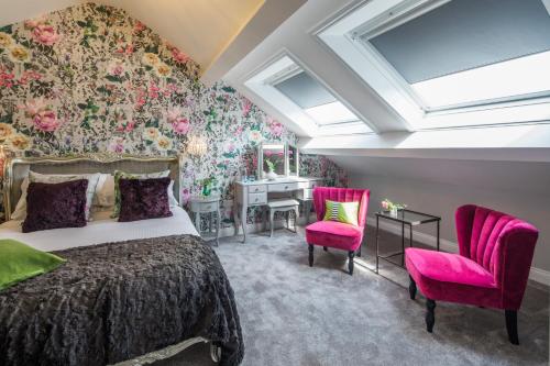 a bedroom with a bed and two pink chairs at 1863 Restaurant with Rooms in Pooley Bridge