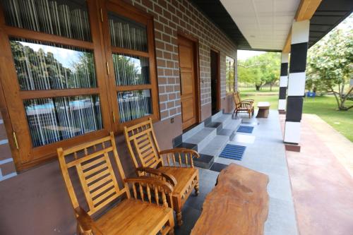 a porch with wooden chairs and windows on a building at Eco Hotel Black & White - Anuradhapura in Mihintale