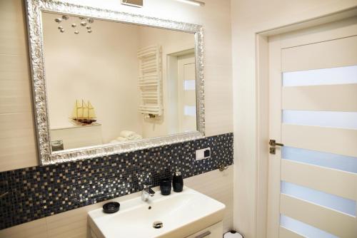 a bathroom with a sink and a mirror at Apartament Szmaragdowy in Ustronie Morskie