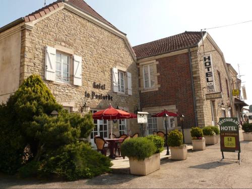 a building with a table and umbrellas in front of it at La Poularde in Louhans