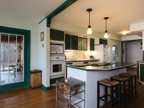 North Hero的住宿－Home Away from Home，厨房配有绿色橱柜和带吧台凳的台面