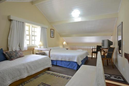 a hotel room with two beds and a tv at Pousada Vila das Cores in Campos do Jordão