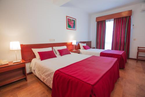 a hotel room with two beds with red sheets at Hotel Cristo Rei - Fatima in Fátima