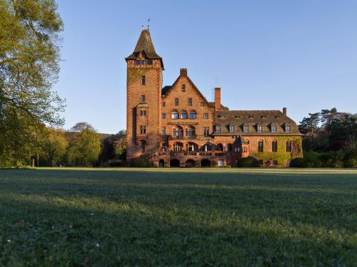 a large building with a clock tower in the middle of a field at Gästehaus Schloss Saareck in Mettlach