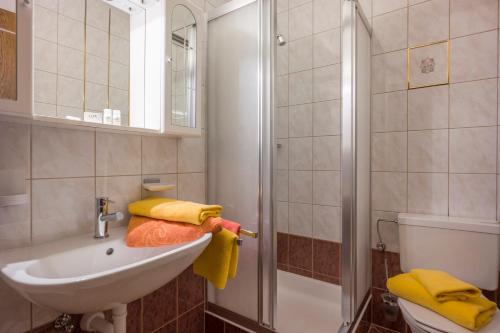 ein Badezimmer mit einem Waschbecken und einer Dusche mit gelben Handtüchern in der Unterkunft Gästehaus Gisela in Bruck am Ziller