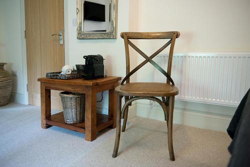 uma cadeira de madeira ao lado de uma mesa com um espelho em The George Great Oxendon em East Farndon