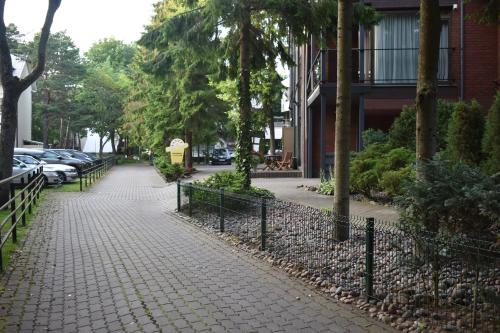a sidewalk with cars parked next to a building at Saulės Krantas in Palanga