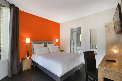 a bedroom with a bed with an orange wall at Hotel Douglas in Puteaux