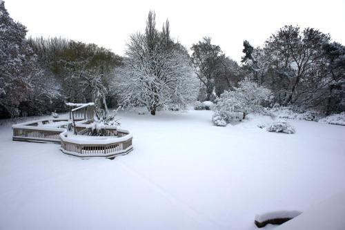 a yard covered in snow with trees and bushes at Claverton Hotel in Battle