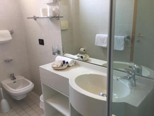 a white bathroom with a sink and a toilet at Hotel La Conchiglia in Bellaria-Igea Marina