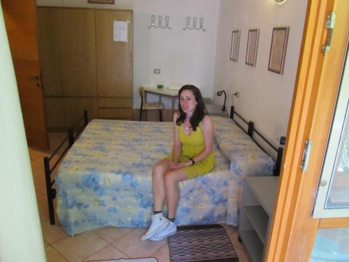 a girl in a yellow dress sitting on a bed at B&B da NINA in Sabbioneta