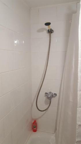 um chuveiro com uma mangueira numa casa de banho branca em Alexandra Park Town House 223 em Belfast