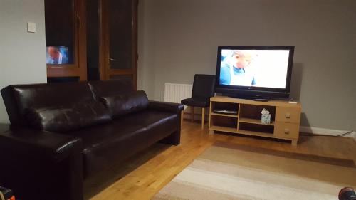 a living room with a black leather couch and a television at Alexandra Park Town House 223 in Belfast
