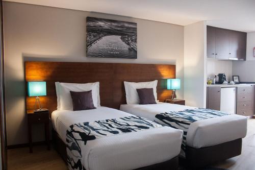a hotel room with two beds and two lamps at Nations Porto - Studios & Suites in Porto