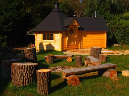 a small cabin with logs in front of it at Chalupa za Křížkem in Malá Morávka