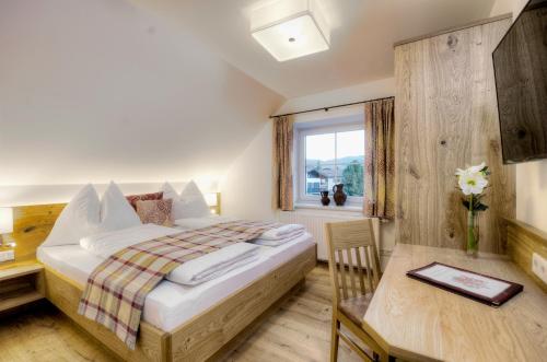Schlafzimmer mit einem Bett, einem Tisch und einem Fenster in der Unterkunft Gasthaus Brandlwirt in Saalfelden am Steinernen Meer