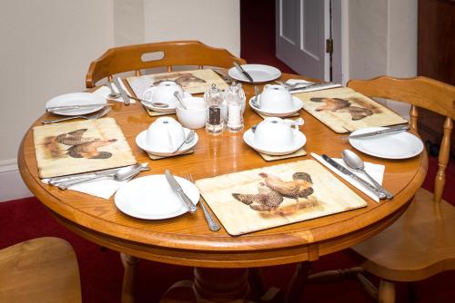 a wooden table with plates and utensils on it at Ammonite Lodge in Chard