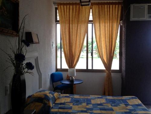 a bedroom with a bed and a window and a chair at Hotel Paraiso in Tepic