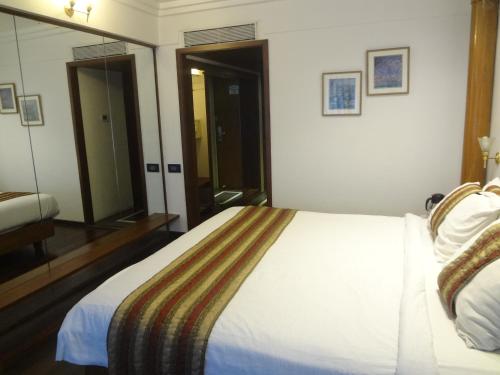 a hotel room with a bed and a mirror at Hotel Midtown Pritam in Mumbai