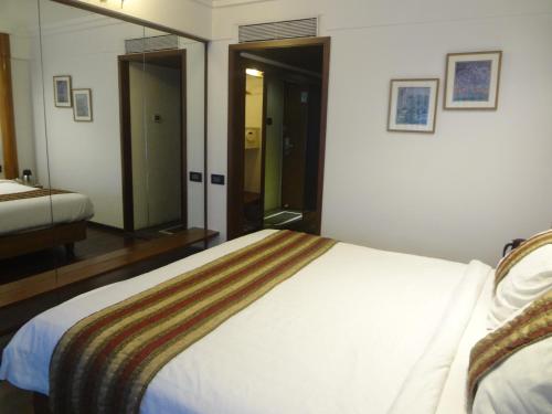 a bedroom with a large bed and a bathroom at Hotel Midtown Pritam in Mumbai
