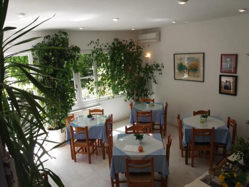 um restaurante com mesas, cadeiras e plantas em Heracles Hotel em Spílion