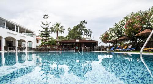 a swimming pool at a resort with chairs and umbrellas at Vallian Village Hotel in Paradeísion