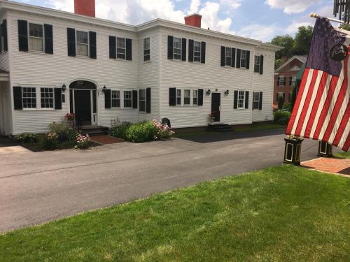 a large white house with an american flag in the yard at The Inn at Montpelier in Montpelier