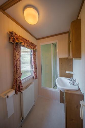 a bathroom with a sink and a window at Domek Promyk in Jurata