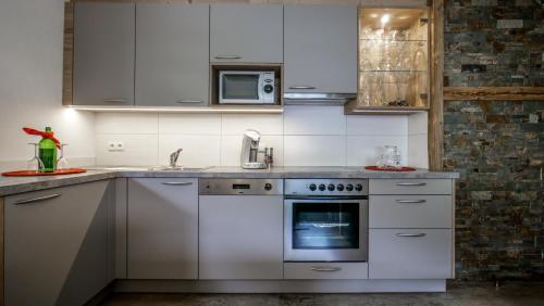 a white kitchen with a stove and a microwave at Apart Tyrol in Uderns