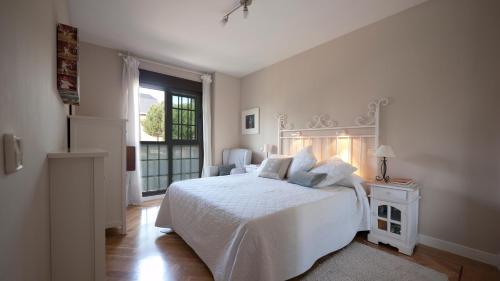 a white bedroom with a white bed and a window at Golf Apartment in Majadahonda