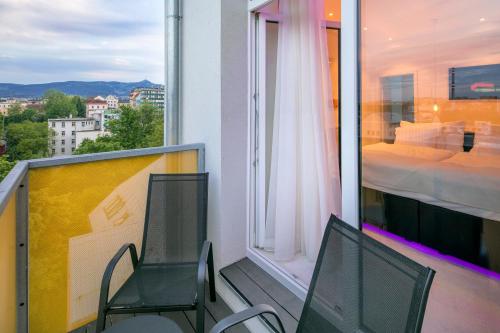 a balcony with two chairs and a bed and a window at Pytloun Grand Hotel Imperial in Liberec