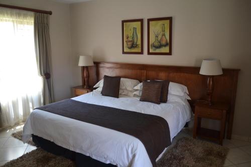 a bedroom with a large bed with white sheets and pillows at Eagles Nest Lodge in Johannesburg
