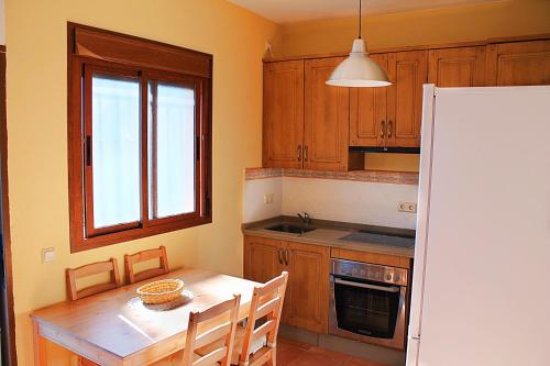 a kitchen with a table and a white refrigerator at Casa Rural Fuente Caraila in Júzcar